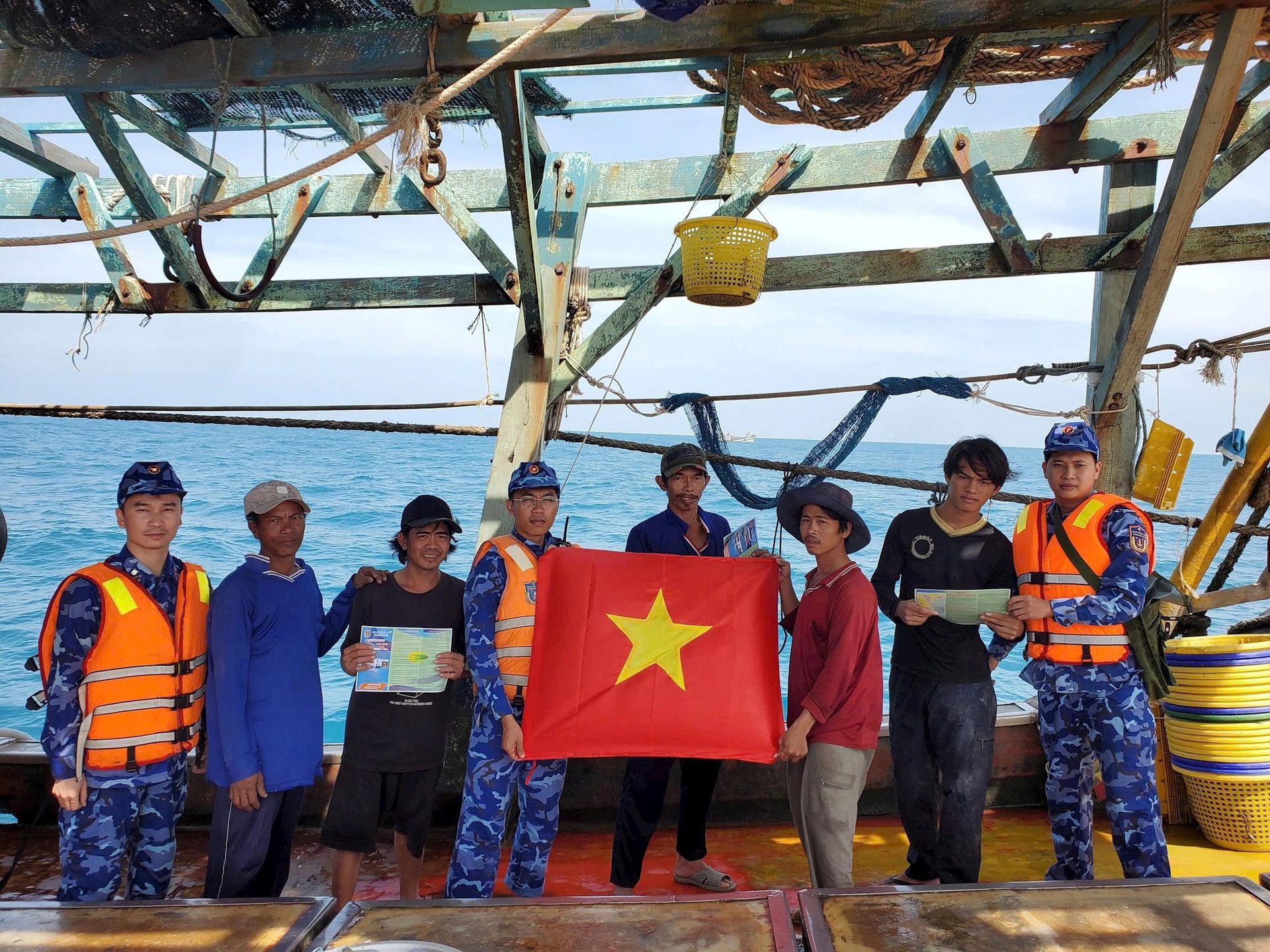 Tàu Cảnh sát biển thuộc Hải đoàn 21 tặng cờ Tổ quốc và phát tờ rơi tuyên truyền chống khai thác IUU cho ngư dân khai thác hải sản trên biển. Ảnh: HẢI ĐĂNG