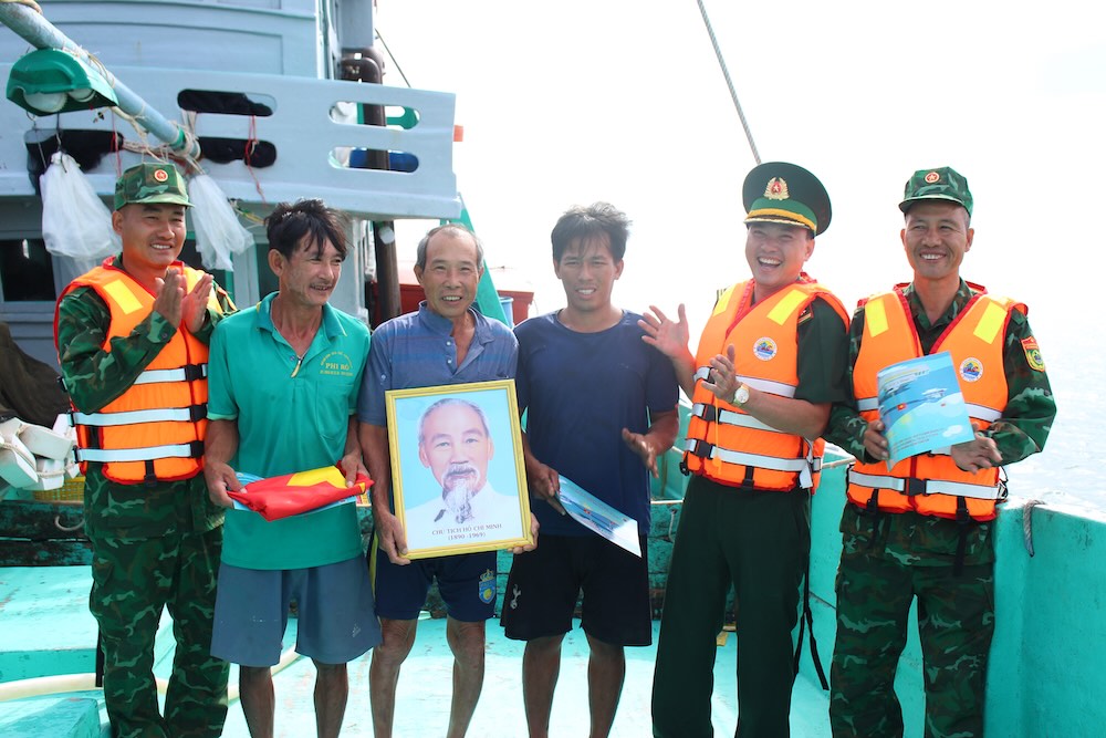 Các ngư dân trên vùng biển Phú Quốc nhận ảnh Bác, cờ đỏ sao vàng sau khi được lực lượng Trạm Biên phòng Cửa khẩu Cảng Dương Đông tuyên truyền chống khai thác IUU. Ảnh: Lục Tùng. 