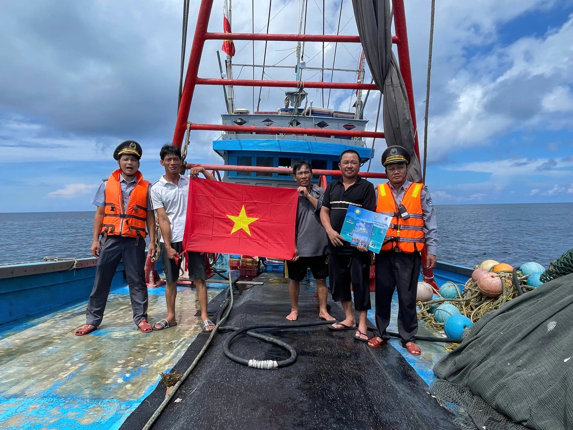 Lực lượng Kiểm ngư phát tờ rơi, tặng cờ cho ngư dân. Ảnh: MP.