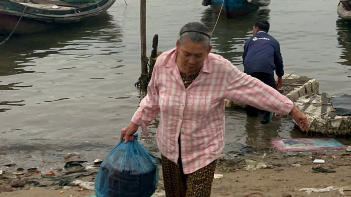 Người phụ nữ xách mực từ ghe của chồng mới cập bờ để kịp ra chợ bán.