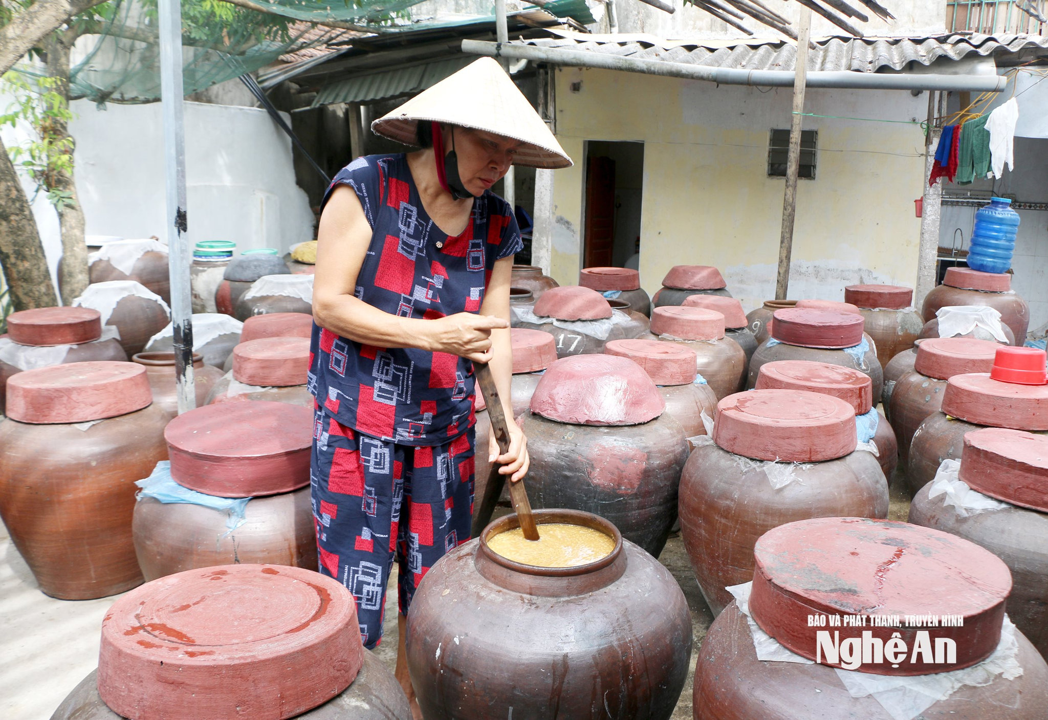 Bà Nguyễn Thị Hồng ở khối Mai Hắc Đế, xã Vạn An khuấy tương trong những chum sành lớn vào mỗi buổi sáng. Ảnh KL
