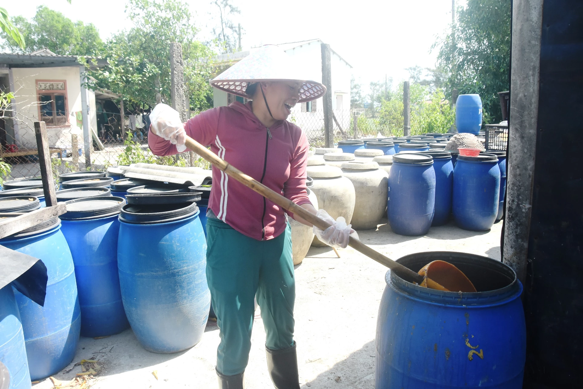 Đảo đều chượp mắm được ủ trong những chiếc thùng nhựa- Ảnh: Đ.V